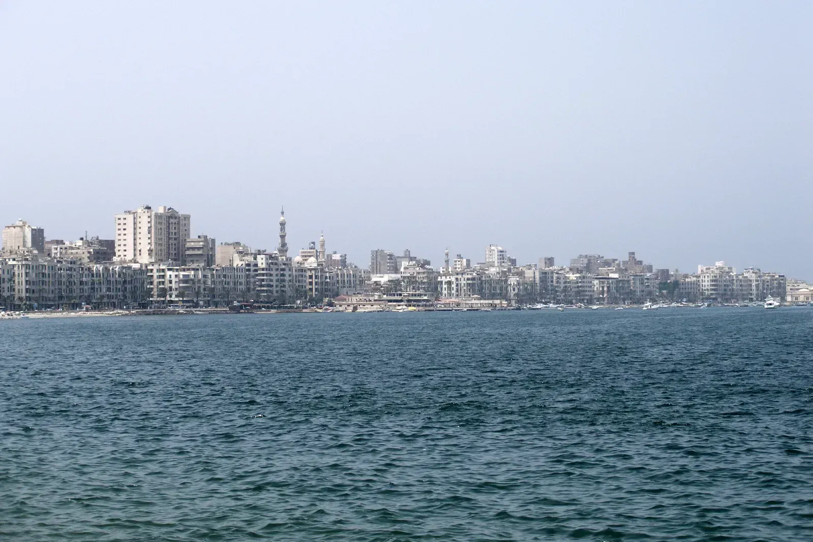 Alexandria's waterfront skyline of apartment buildings and a mosque minaret seen across the harbor.