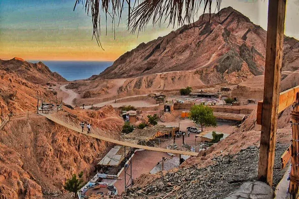 Seilhängebrücke über eine schroffe Wüstenschlucht bei Dahab mit Beduinencamp und Blick auf das Rote Meer