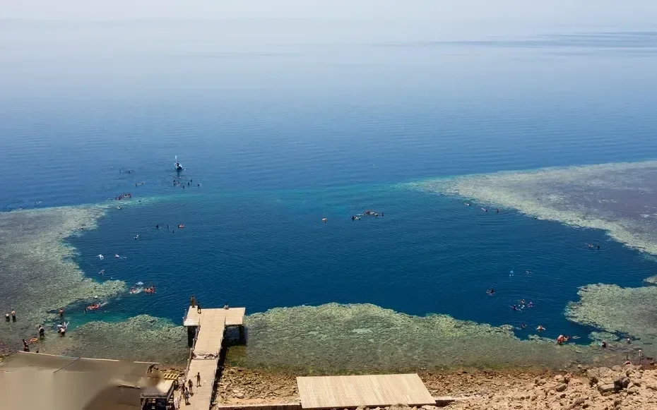 Magaslati nézet a Blue Hole lagúnájában szétszóródott snorkelezőkről egy fa móló közelében