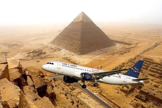 Digitaal samengesteld beeld van een Air Cairo-passagiersvliegtuig dat spectaculair laag boven de Grote Piramide vliegt
