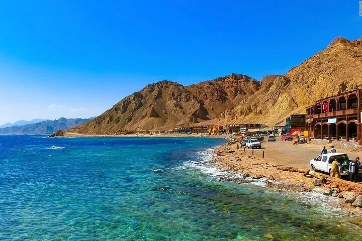 Türkisfarbenes Flachwasser und Kieselstrand am Blue Hole in Dahab unter braunen Bergen