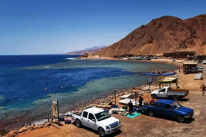 Pick-ups am Ufer des Blue Hole in Dahab neben Cafés, dahinter Meer und Berge