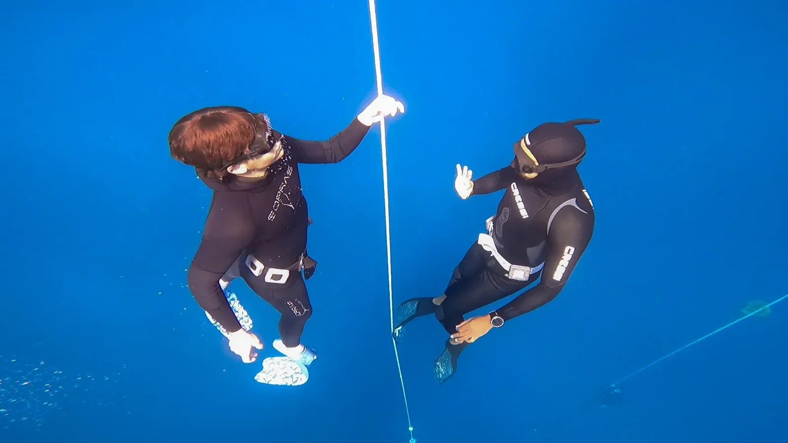 Freediving-Lehrer und Schüler halten die Abstiegsleine im tiefblauen Wasser während einer Lektion