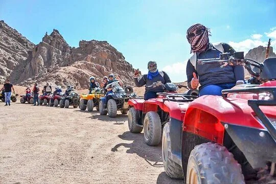 Pilotes de quad au visage couvert faisant le pouce levé à l'arrêt près d'un affleurement rocheux