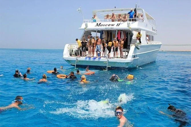 Snorkelers in the water beside the dive boat Moscow II, several people swimming and jumping in.