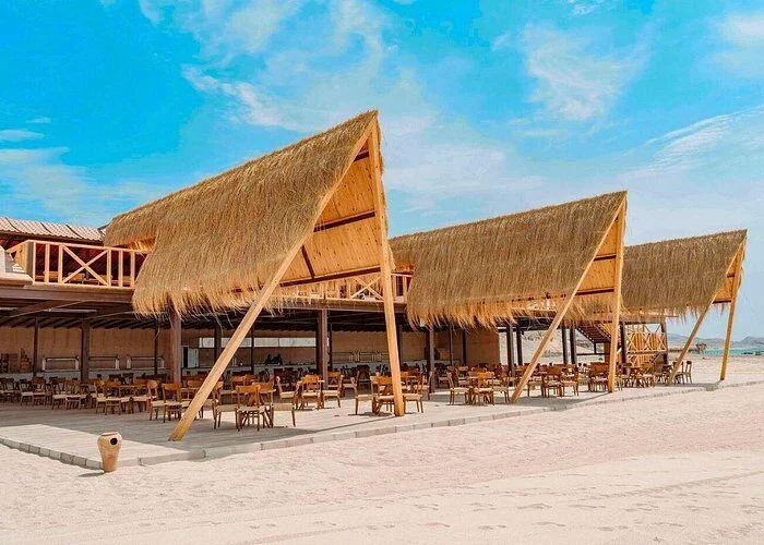 Driehoekige paviljoens met rieten dak met een openluchtrestaurant met houten tafels en stoelen op het strand