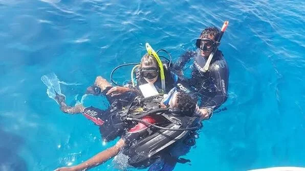 Zwei Taucher in Neoprenanzügen schleppen bei einer Rettungsübung im Wasser einen dritten Taucher