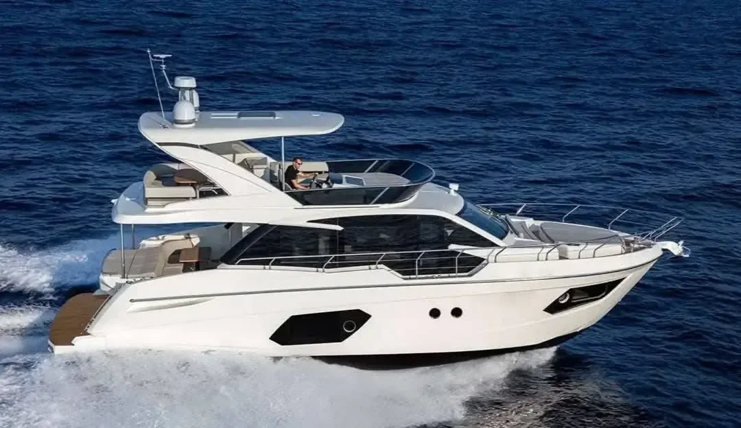 Vue aérienne d'un yacht à moteur de luxe filant à vive allure, une personne pilotant depuis le flybridge ouvert