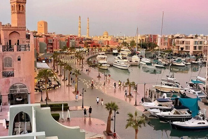 Vue en hauteur de la marina de Hurghada au crépuscule, ciel rose et bateaux amarrés le long du front de mer courbe