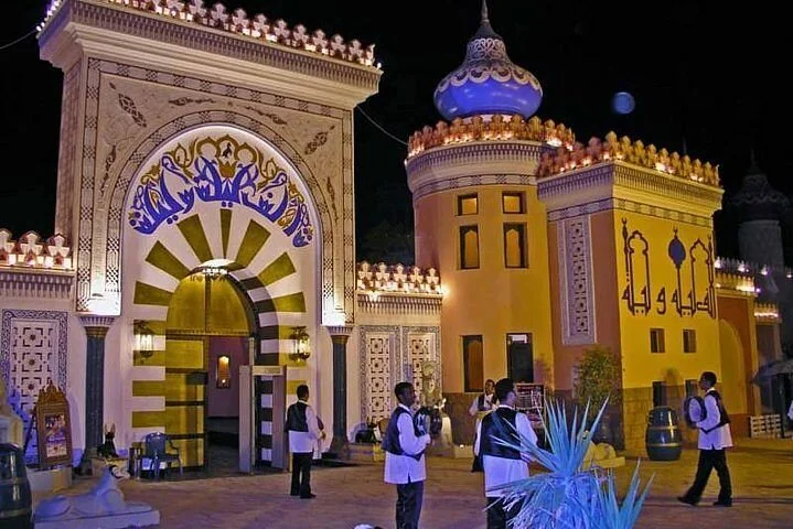 Prunkvoll beleuchtetes Tor und Türme im arabischen Stil bei Nacht, Personal geht nahe dem Eingang