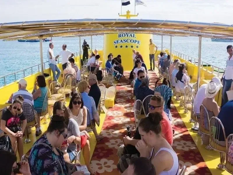 Passagiere sitzen an Tischen auf dem gelben Oberdeck der Royal Seascope, die vor Hurghada auf See fährt
