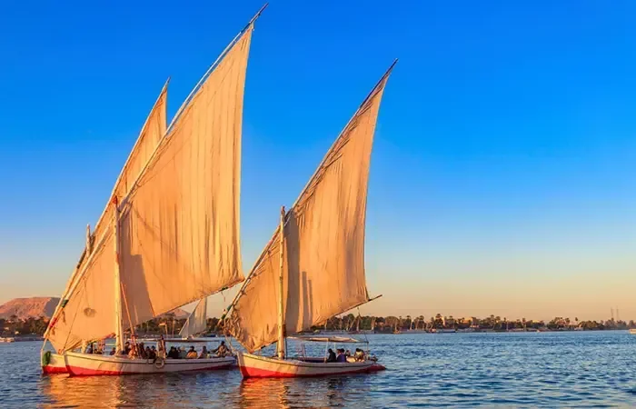 Két felucca krémszínű vitorlával a Níluson Luxornál kék ég alatt