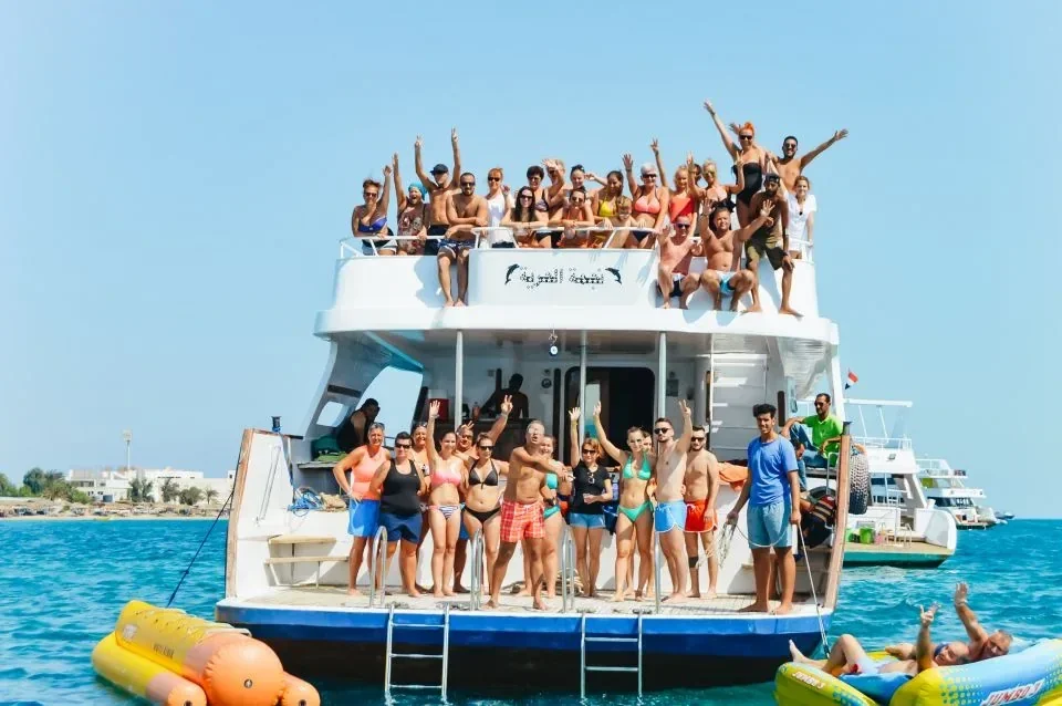 A large tour boat packed with cheering passengers on its upper deck