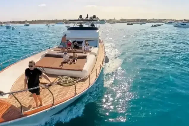 Luxus motoros jacht napozó utasokkal a párnázott üléseken halad el egy forgalmas kikötő mellett