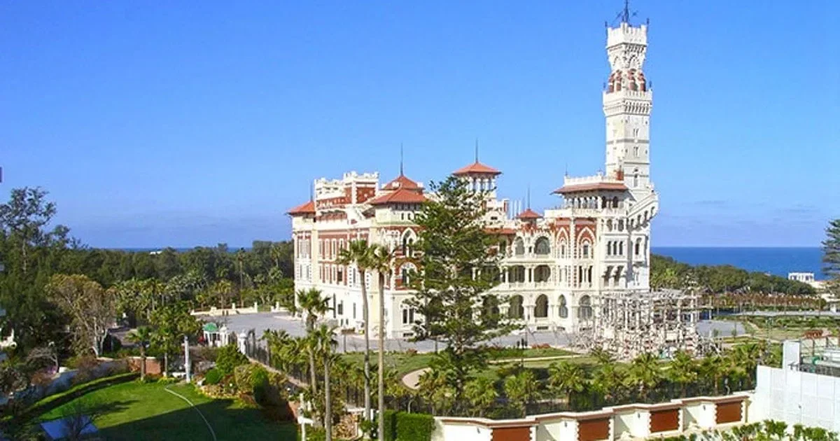 Elevated view of the full palace complex and grounds with the Mediterranean coastline visible in the background.