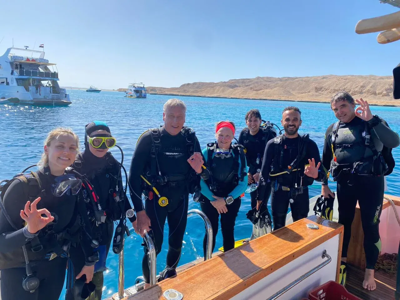 Groep van zeven duikers poseert op het dek van een duikboot met OK-tekens