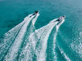 Luchtfoto van twee speedboten die naast elkaar over turquoise water racen en parallelle witte kielzogen achterlaten