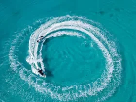 Luchtfoto van een speedboot die een strakke cirkelvormige kielzog in turquoise water trekt