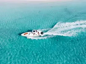 Luchtfoto van een enkele speedboot die dicht bij de kust door ondiep turquoise water snijdt