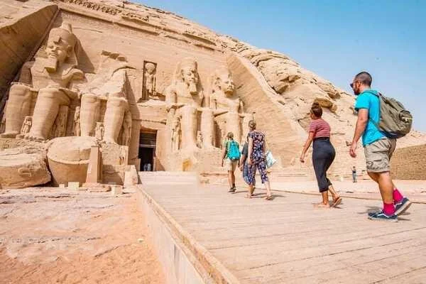 Kleine Touristengruppe geht auf dem Weg zu den sitzenden Kolossalstatuen am Eingang des Großen Tempels von Abu Simbel