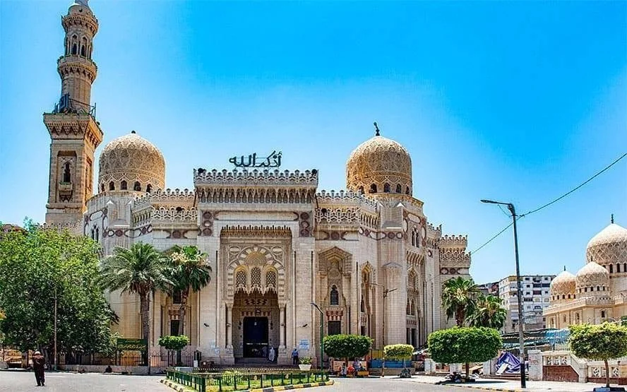 Exterior of the Abu al-Abbas al-Mursi Mosque with ornate domes and a tall minaret against a clear blue sky