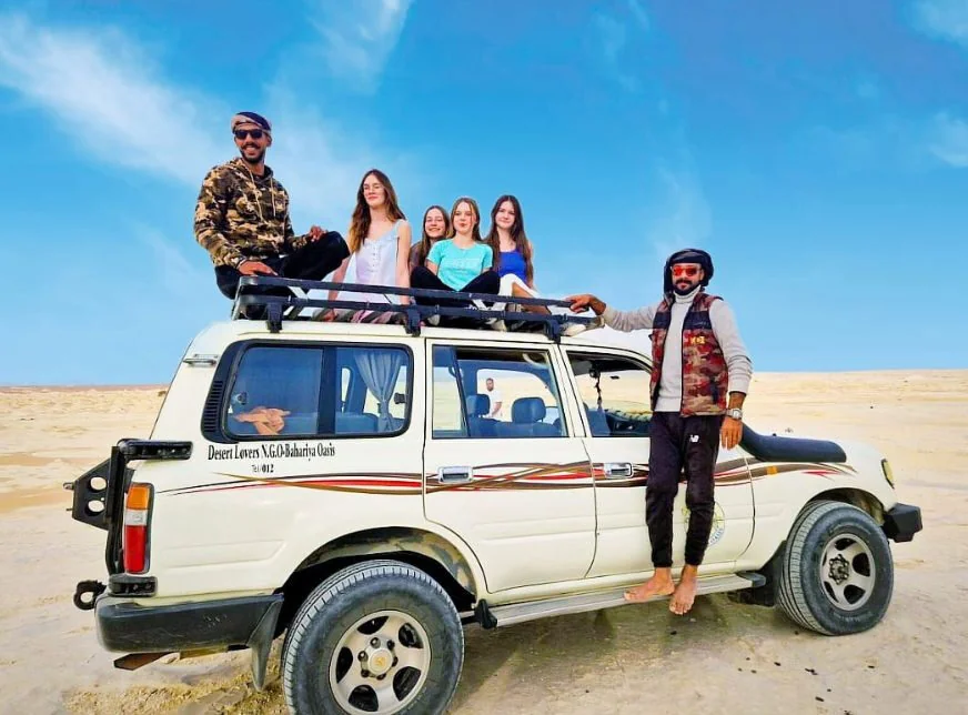 Sechs Personen auf und neben einem weißen Geländewagen der Desert Lovers NGO Bahariya Oase in der Wüste