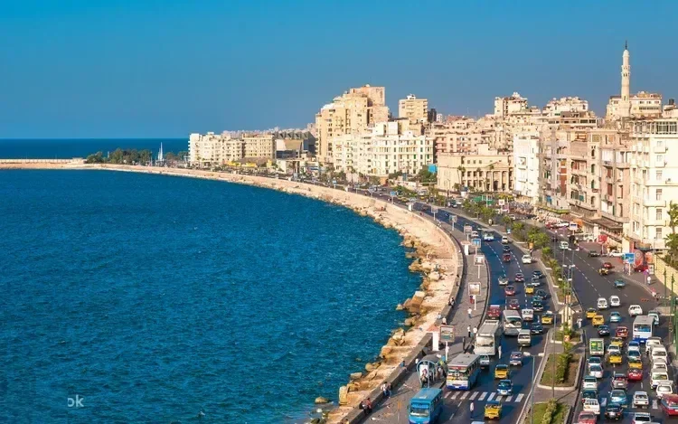 Elevated view of Alexandria's Corniche coastal road curving along the Mediterranean Sea with heavy traffic.