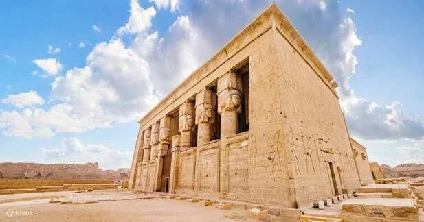 Exterior corner view of the Temple of Hathor at Dendera showing its massive facade and Hathor-head columns against a partly