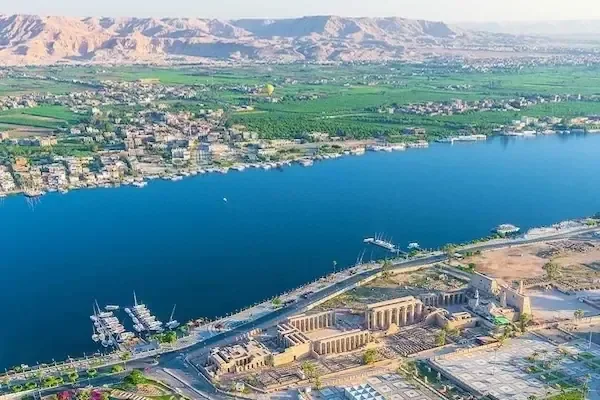 Luchtfoto van de Luxortempel naast de Nijl, omringd door de stad Luxor met bergen in de verte