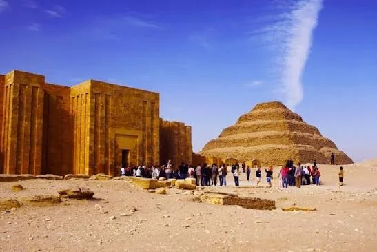 Rondleidingsgroep bij de zuilengang aan de ingang van het grafcomplex van Djoser, met de trappenpiramide erachter