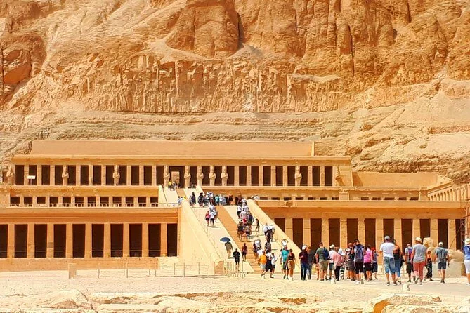 Vue large du temple d'Hatchepsout, touristes gravissant les rampes entre ses colonnades en terrasses