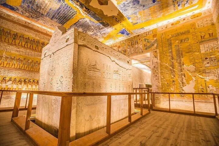 Sarcophage de pierre peint dans une tombe royale, plafond et parois sculptés d'hiéroglyphes aux couleurs vives