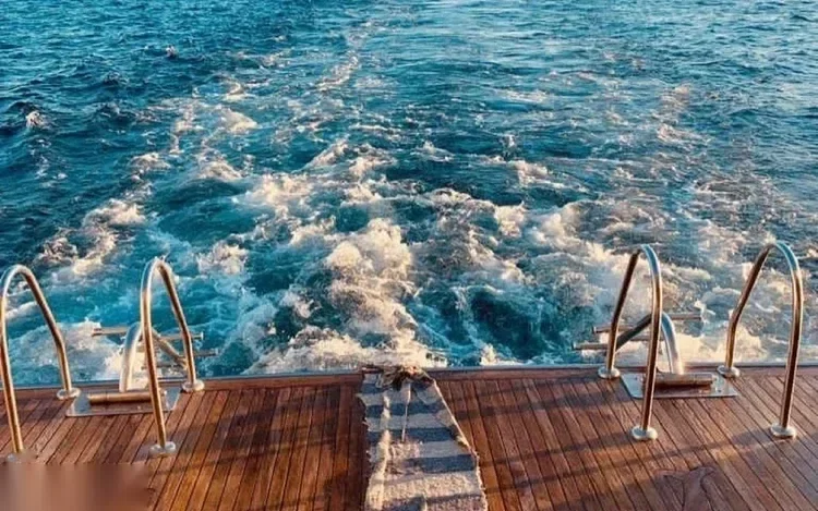 Vue de la poupe d'un bateau avec échelles de plongée et sillage d'eau blanche écumante derrière