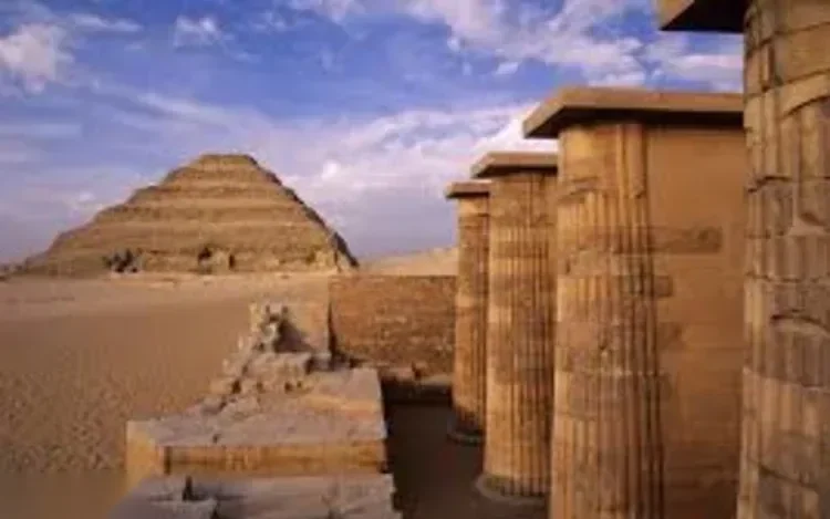 Zicht op de trappenpiramide van Djoser over de woestijn, omlijst door een rij stenen zuilen op de voorgrond