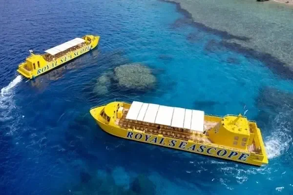 Luftaufnahme zweier gelber Royal-Seascope-Boote, die um ein Korallenriff im türkisfarbenen Wasser fahren