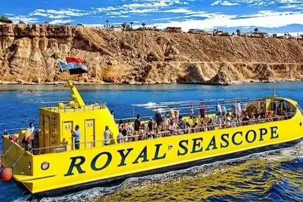 Royal-Seascope-Boot mit ägyptischer Flagge fährt an einer rötlichen Felsküste unter leicht bewölktem Himmel vorbei