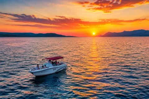Vue aérienne d'un petit hors-bord à auvent avec passagers filant vers un vif coucher de soleil orange