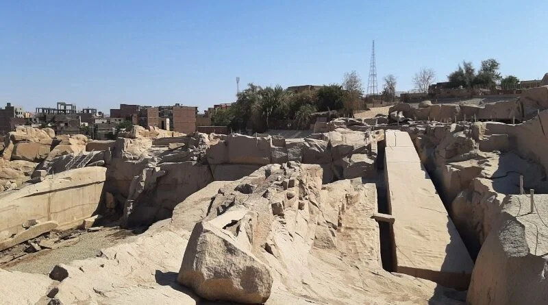 花岗岩采石场的广角视图，显示方尖碑的切割凹槽，远处是阿斯旺的屋顶