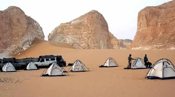 Tentes de camp et 4x4 sous de grands rochers de grès dans le Désert Blanc, étape de nuit du safari depuis Le Caire